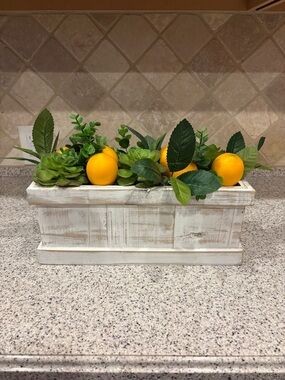 Decorative centerpiece featuring faux lemons and greenery in a white rustic box